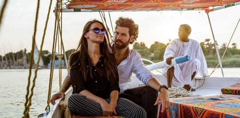 Du khách ngồi trên đệm thuyền Felucca phía sau là sông Nile lúc chiều tà